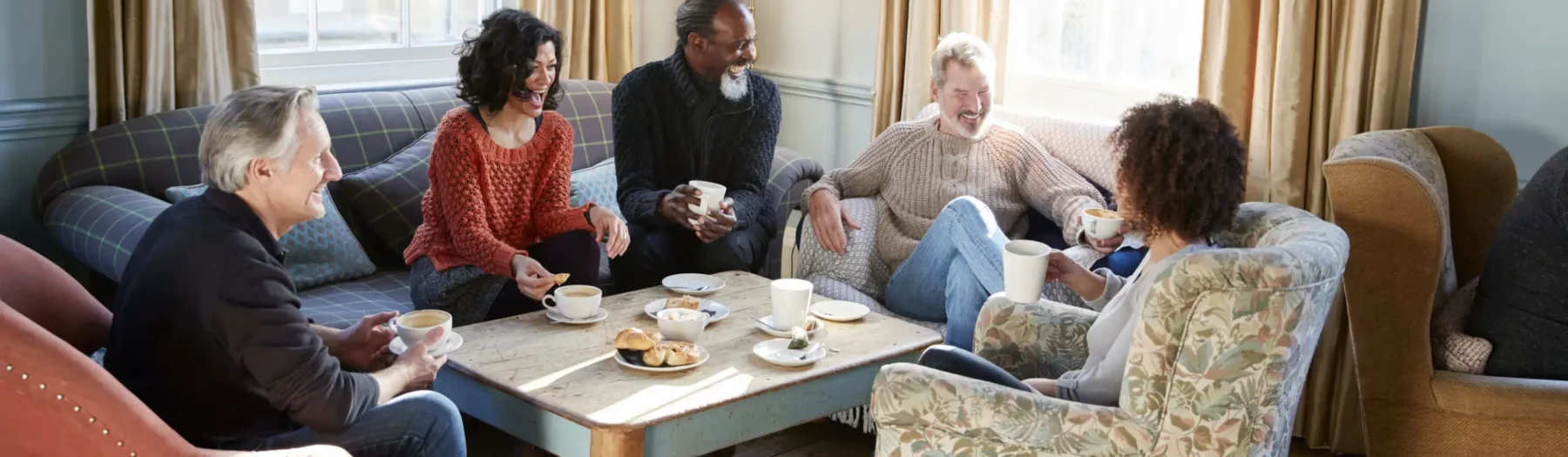 Group of older friends talking around a coffee table