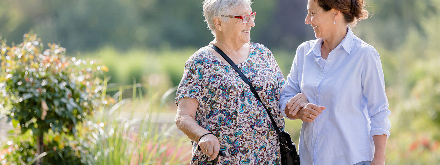 Senior woman walking outside with a resident care assistant