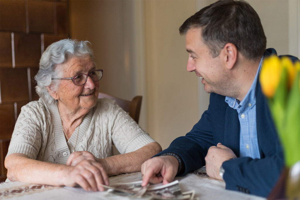Older woman looking at photographs with her adult grandson