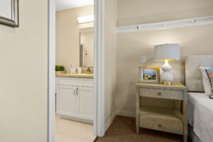 View of bathroom sink and bedside night table in Duxbury House memory care apartment