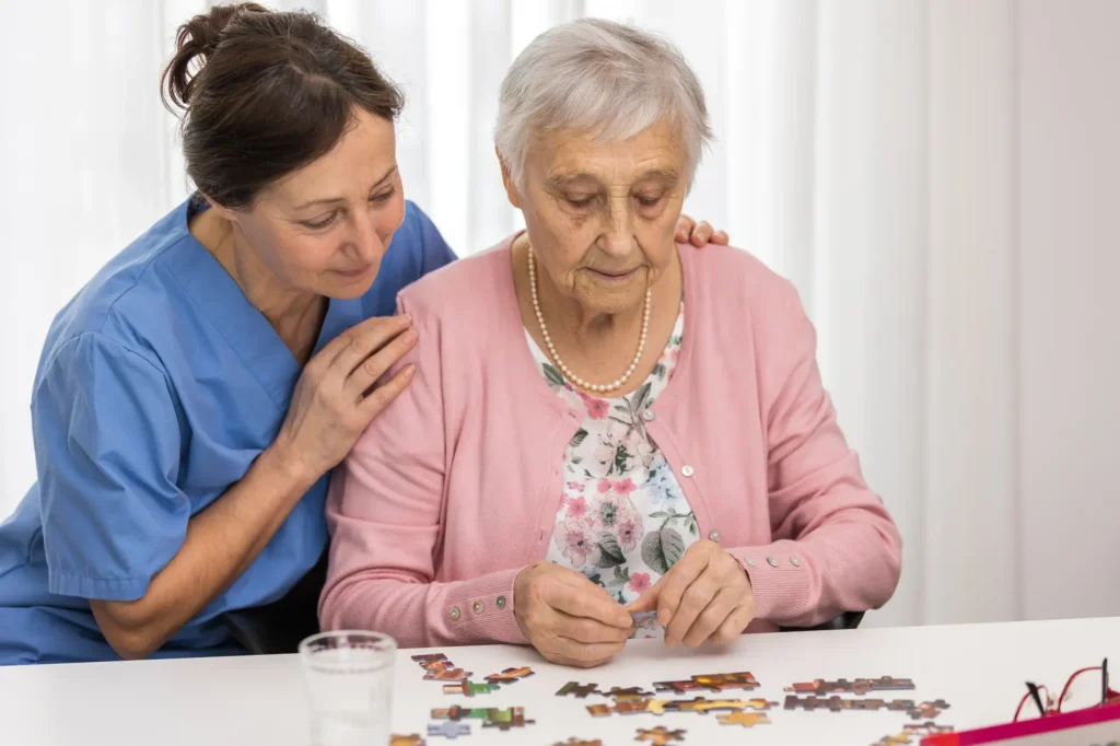 caregiver encourages senior woman as she does a puzzle