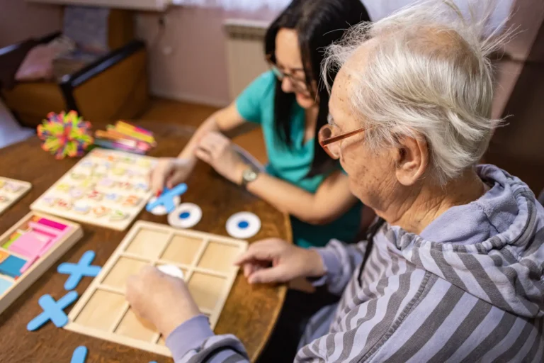 senior man and caregiver play tic-tac-toe and other memory games for dementia