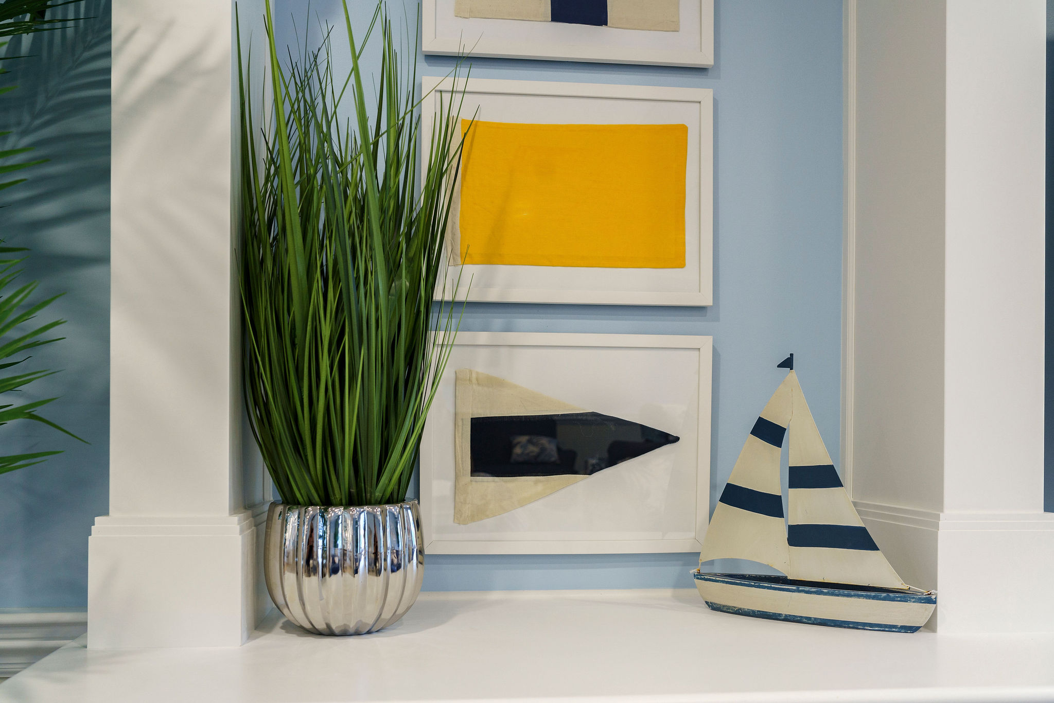 Shelf with plant, sailboat model, and artwork on the wall